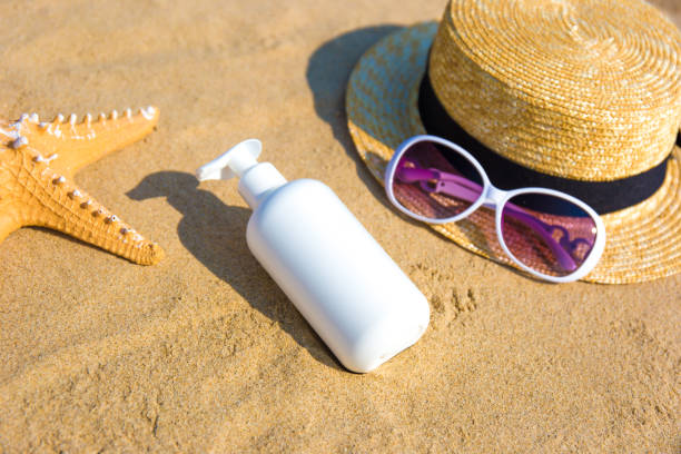 Crème solaire, chapeau de paille et lunettes de soleil sur une plage