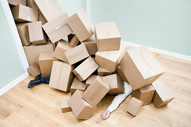 Homme enseveli sous les cartons de déménagement après être tombé par terre