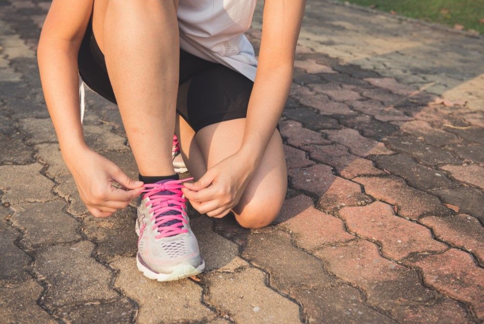 Jeune femme qui lace ses baskets de sport avant d'aller courir